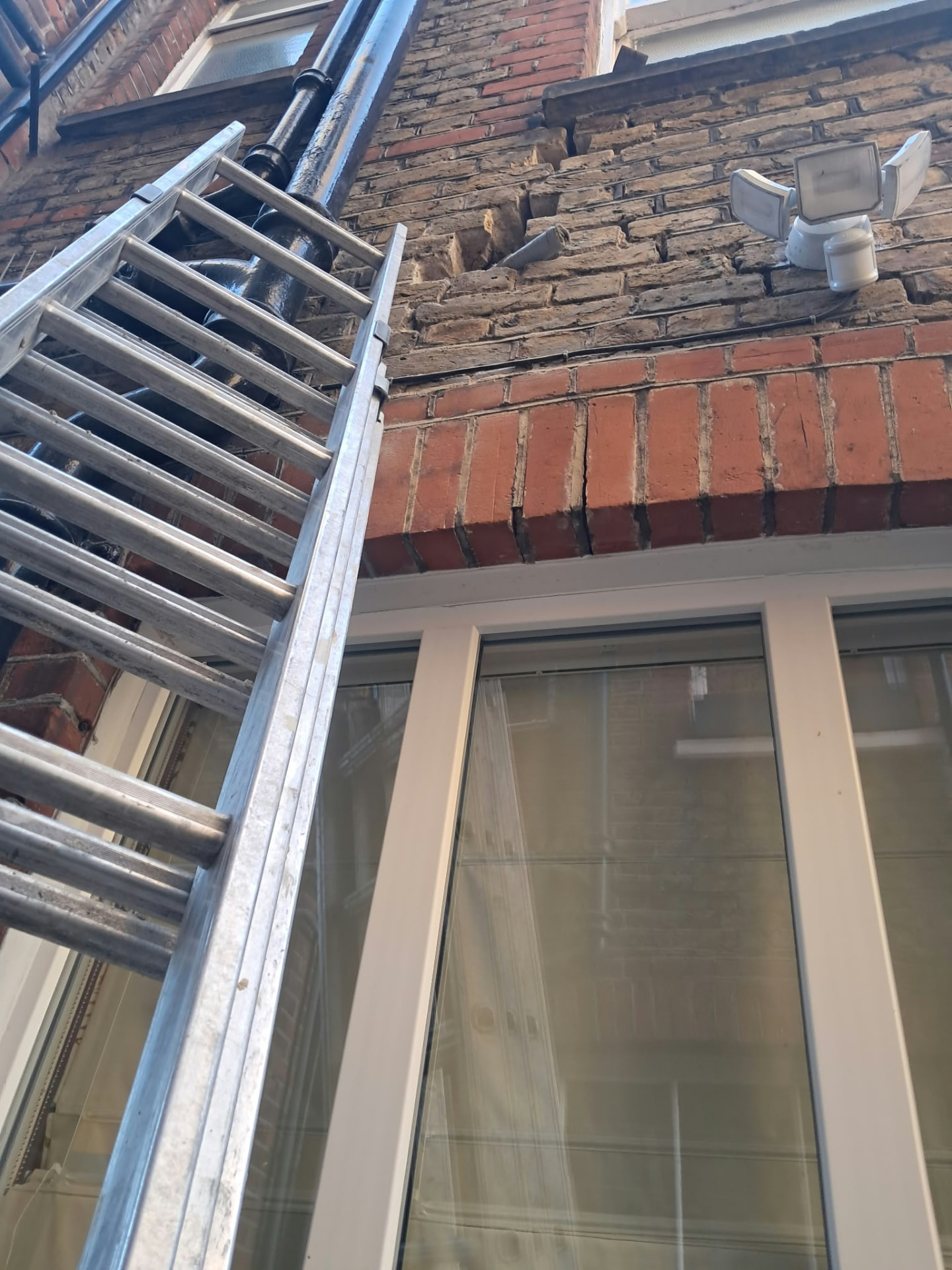 Movement crack running through the brickwork above a window arch in Putney before repair