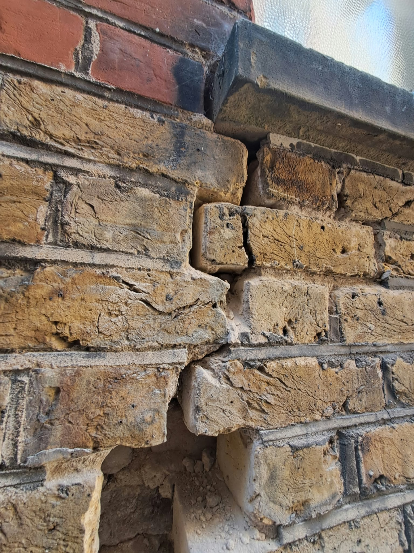 Close-up of a movement crack in the yellow stock brickwork by a window sill in Putney