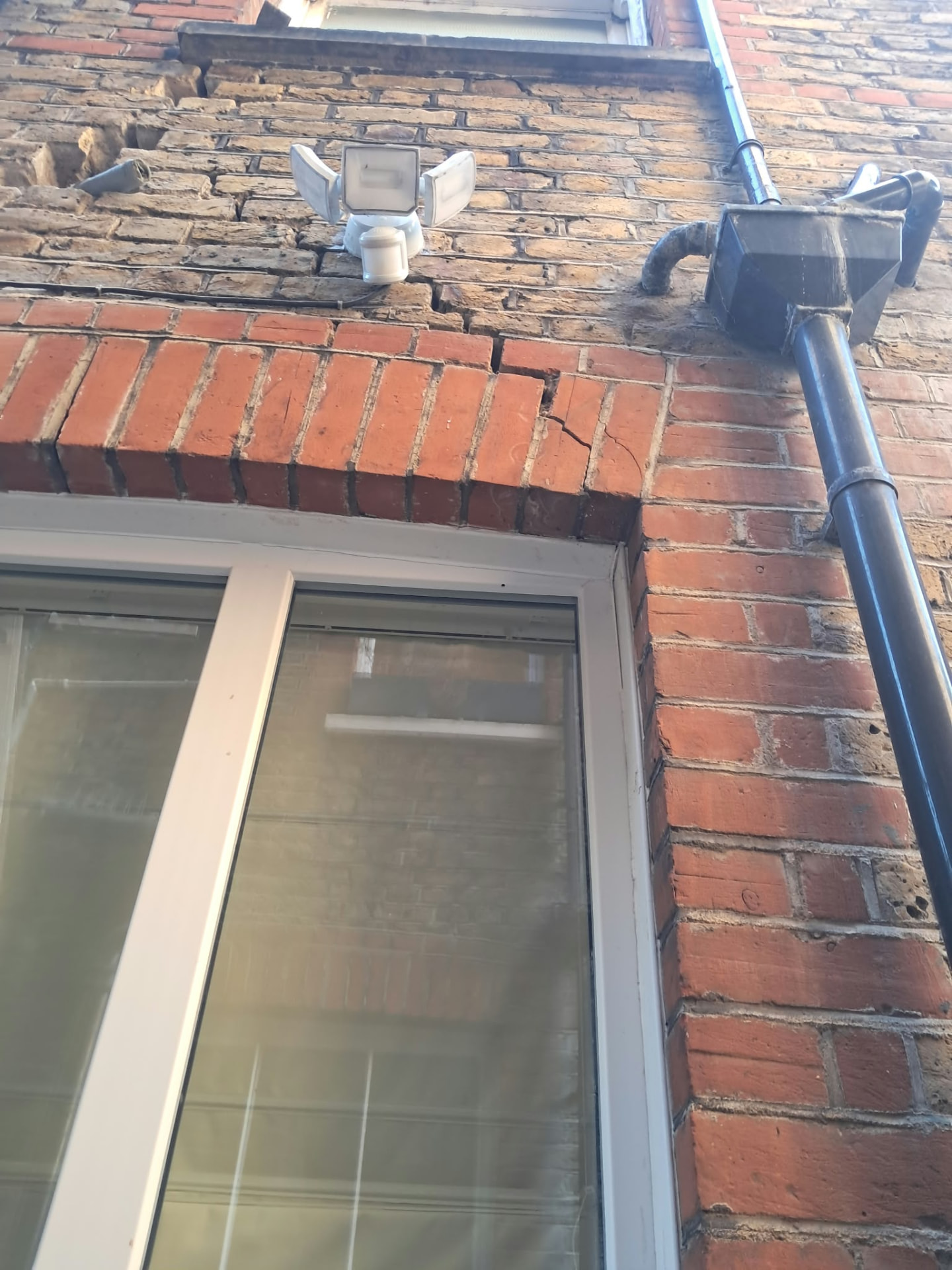 Cracked red brick arch above a window on a Putney house before crack repairs